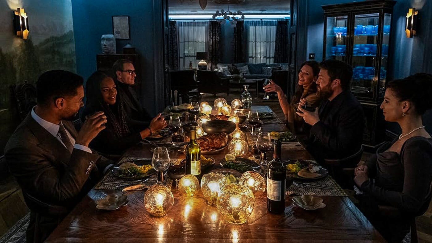 A formal dinner party with eight well-dressed people seated around a long table glowing with candlelit orb lights. The room is dim and cool-toned, with shadows deepening toward the background.