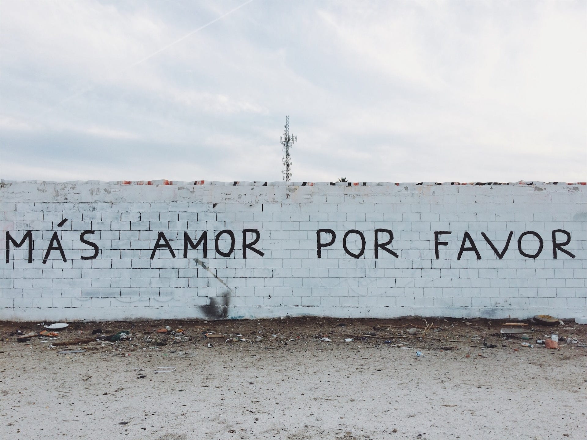 Un muro di mattoni bianchi a Mexicali su cui campeggia la scritta "Más amor por favor"