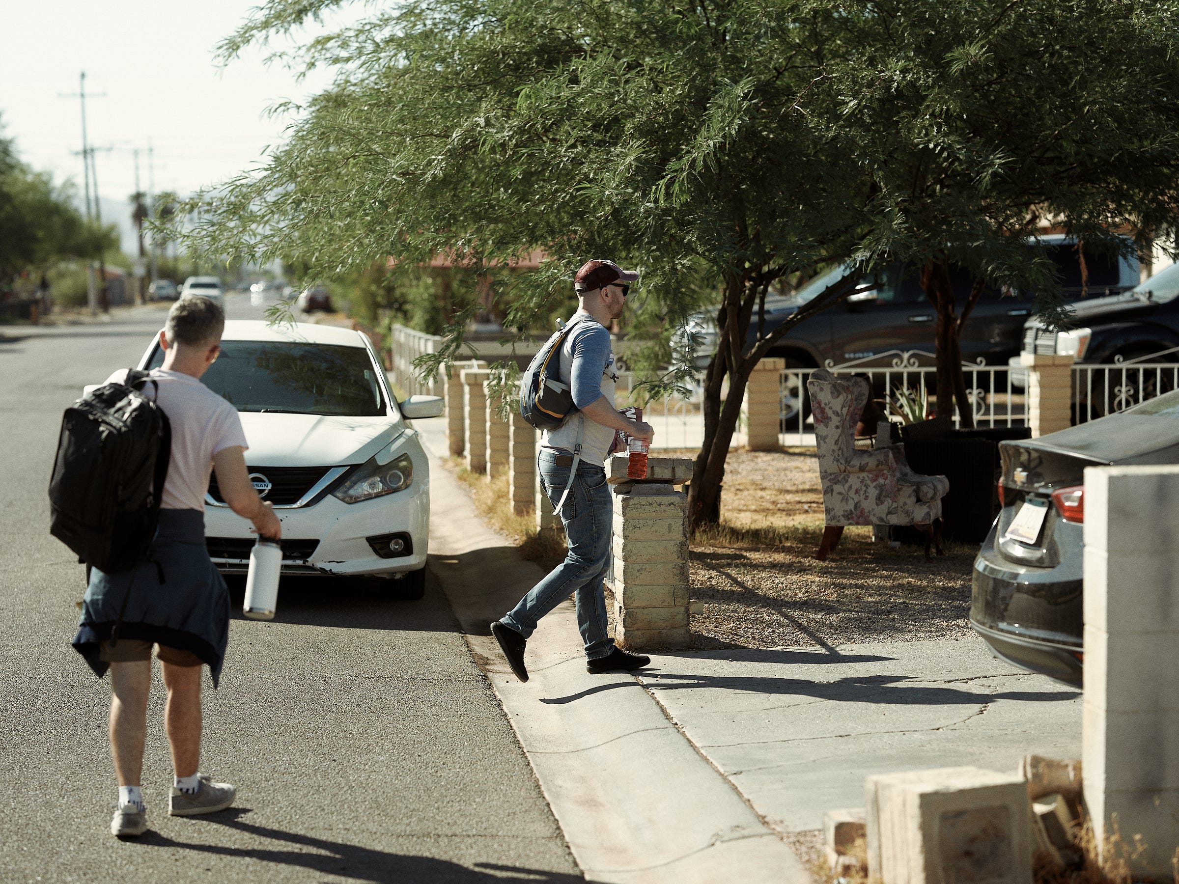 Two men walk up to a house during their morning canvassing shift in Phoenix, AZ photographed by LA documentary photographer Afonso Salcedo