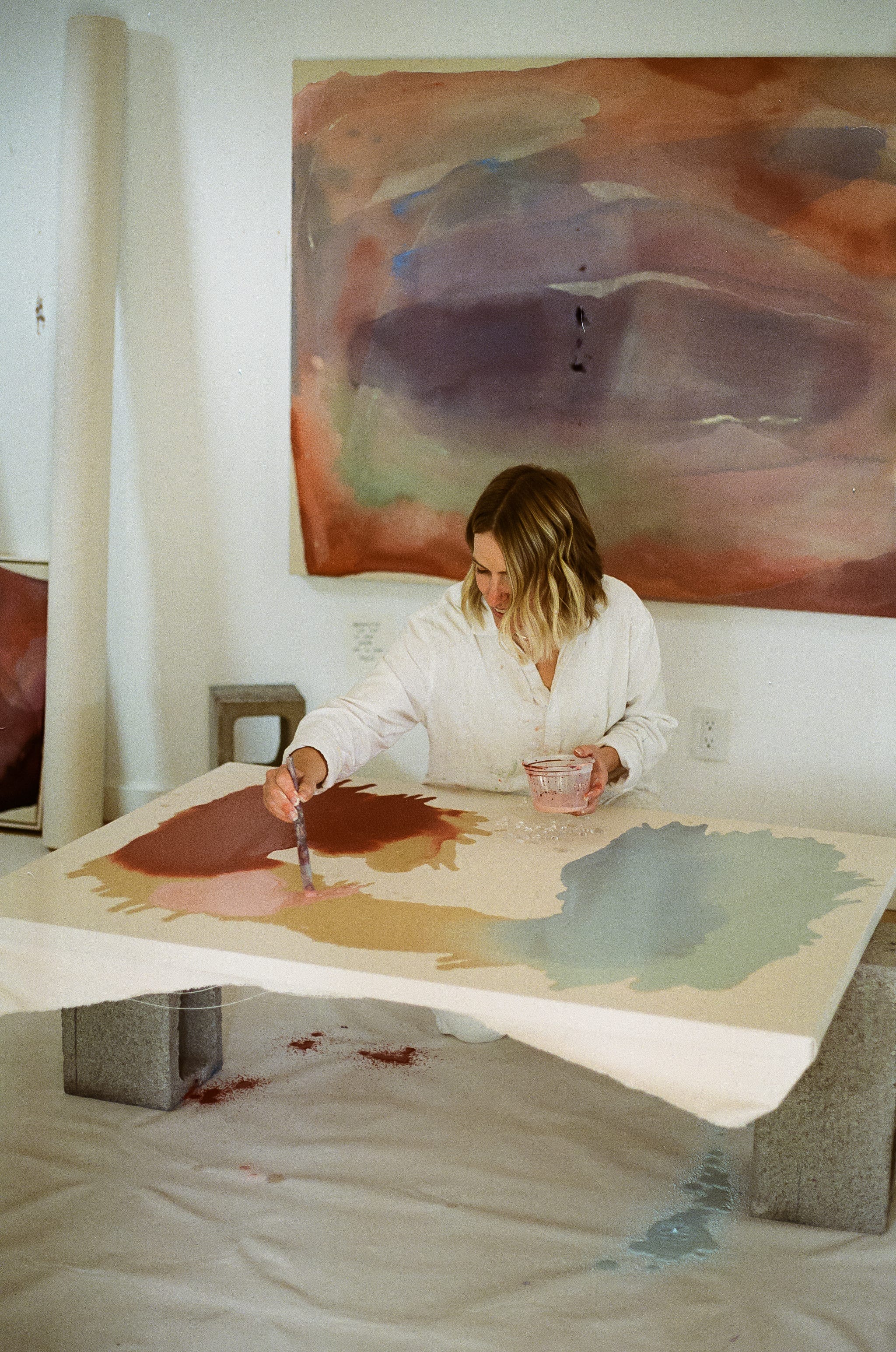 abstract artist Brenna Hodges painting on raw canvas in her home studio in Portland, Oregon