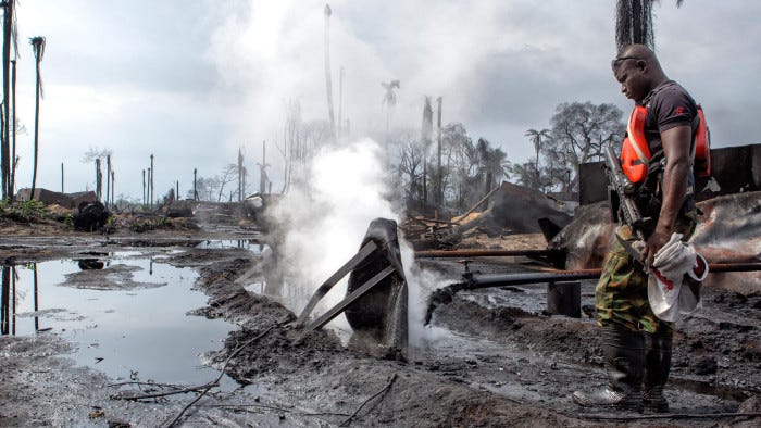 J2R0EP Boiling hot oil is pours into open dikes leading to open air storage pools at the site of an illegal refinery, causing massive pollution, near Port Hartcourt, River State, Nigeria