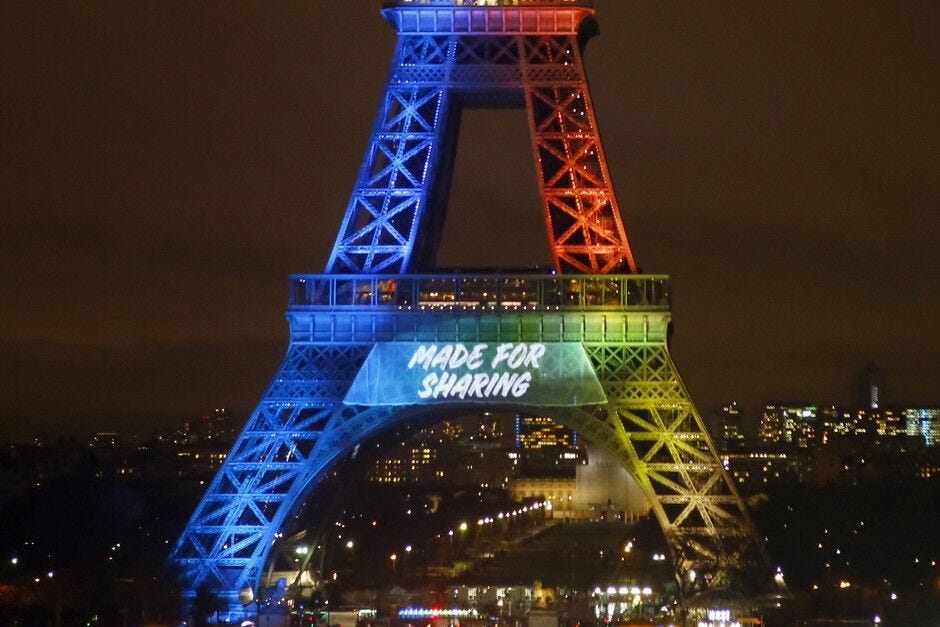 The Eiffel Tower lit up in red and blue with the slogan “Made for Sharing” projected on to it.