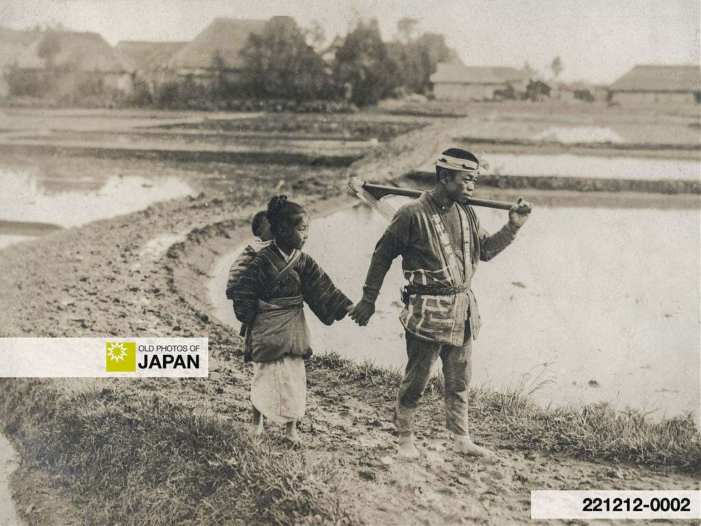 Young Japanese girl carrying an infant is holding the hand of her father, 1910s