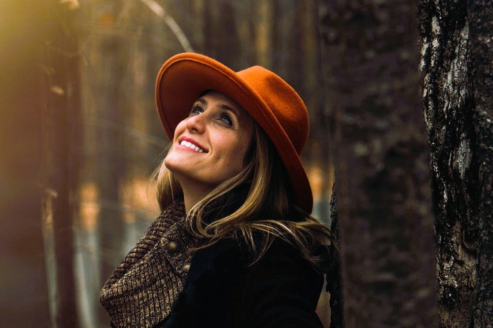 Middle-aged woman wearing a hat looking up at the sky in a forest. Middle-aged woman wearing a hat looking up at the sky in a forest.