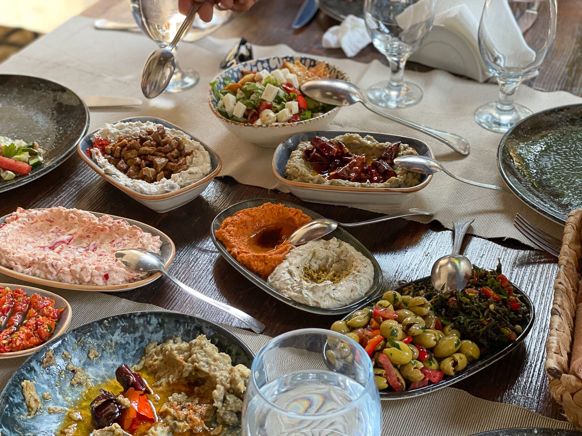 A colourful set of meze dishes on a nicely set dining table in a restaurant.