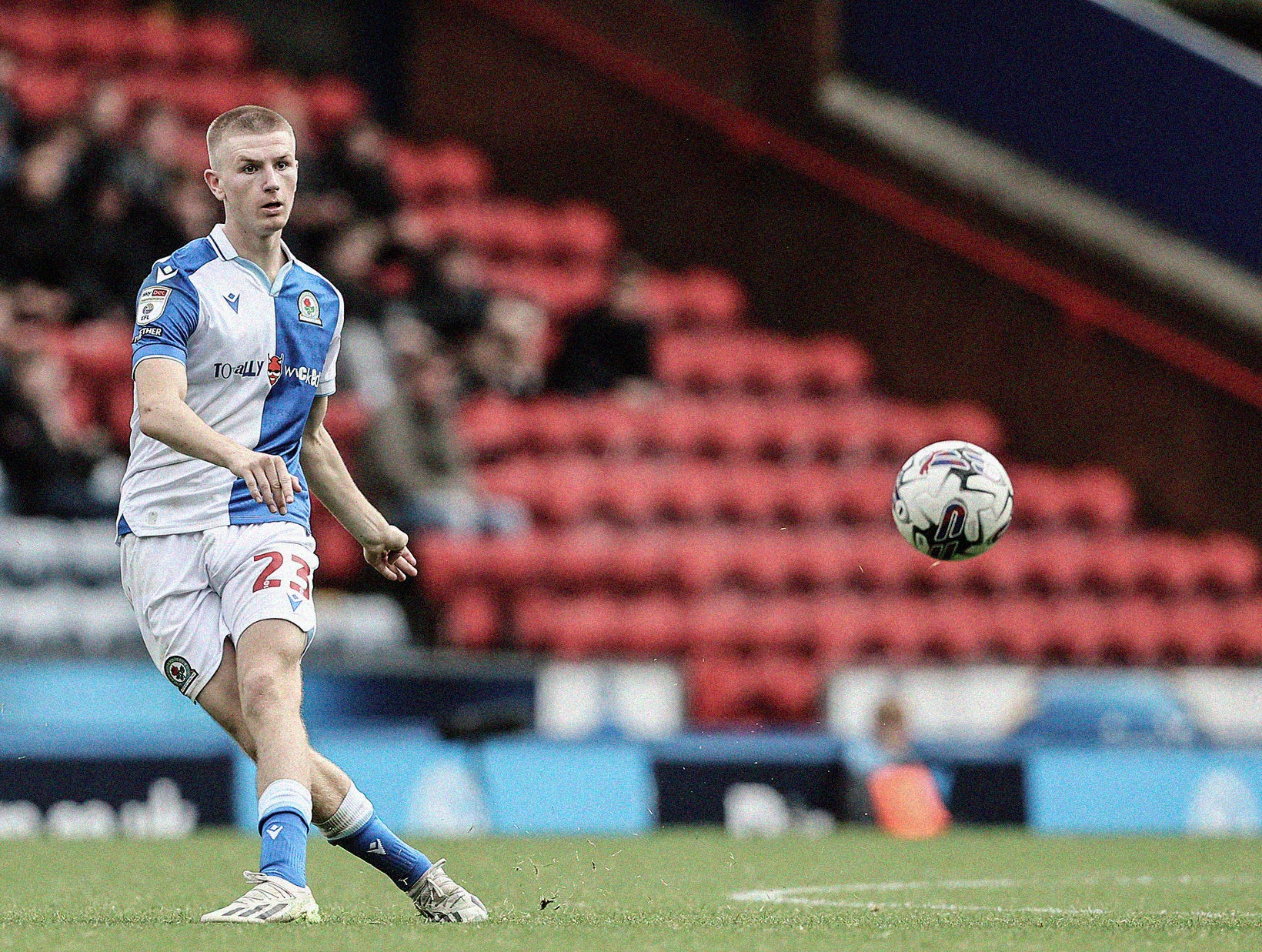 A wide-frame photo of Adam Wharton passing the ball with his left foot.