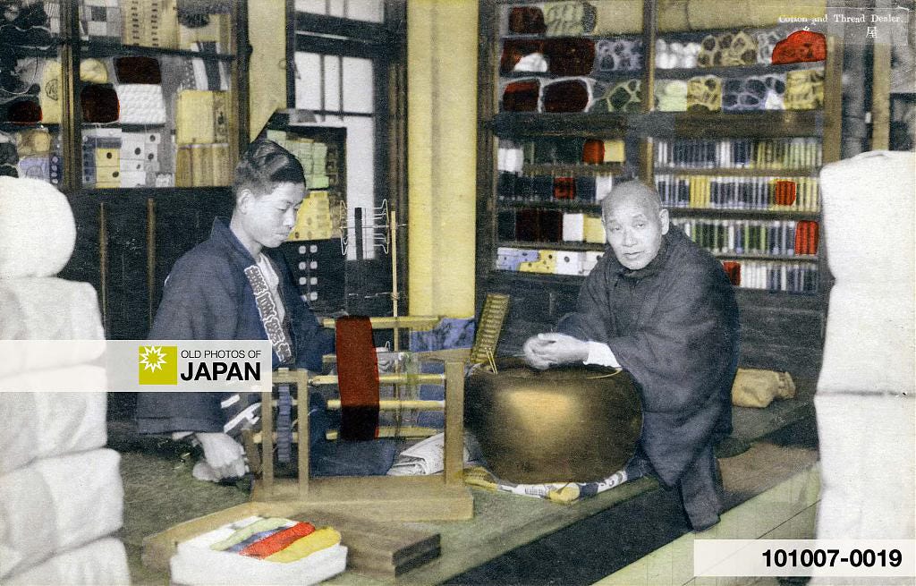 Japanese man warming his hands at a hibachi charcoal brazier at a cotton and thread shop, 1930s. Japanese man warming his hands at a hibachi charcoal brazier at a cotton and thread shop, 1930s.