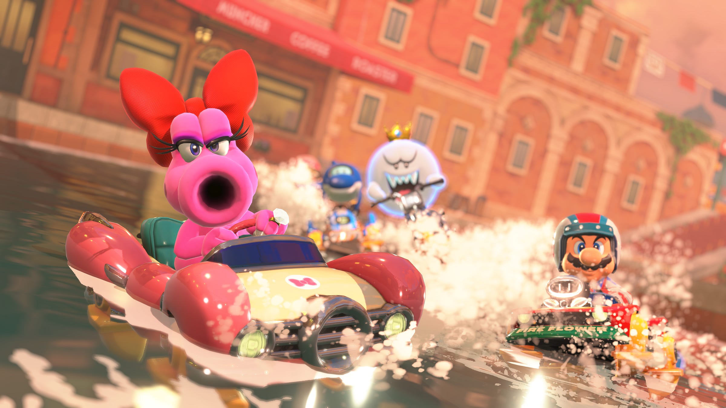Video game screenshot of a pink dinosaur-like creature driving a car over the water, while a ghost and Mario ride vehicles behind her.