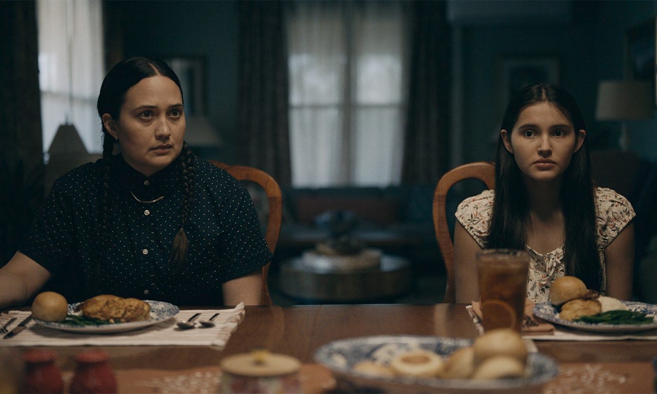 A still from Fancy Dance with Lily Gladstone as Jax and Isabel Deroy-Olson sitting together at a dinner. 
