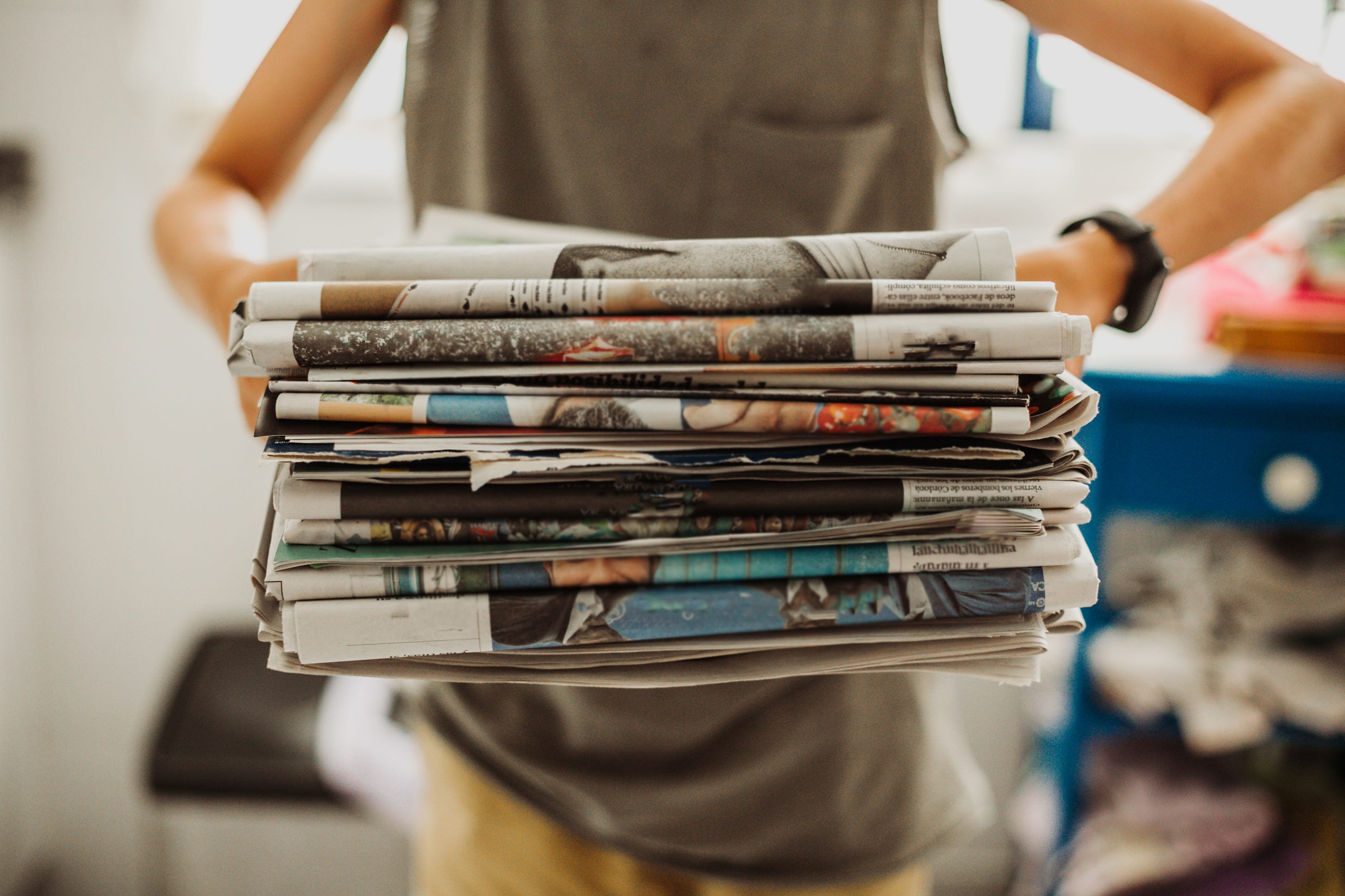 A woman shown from the neck down holding a stack of newspapers (Getty Images)