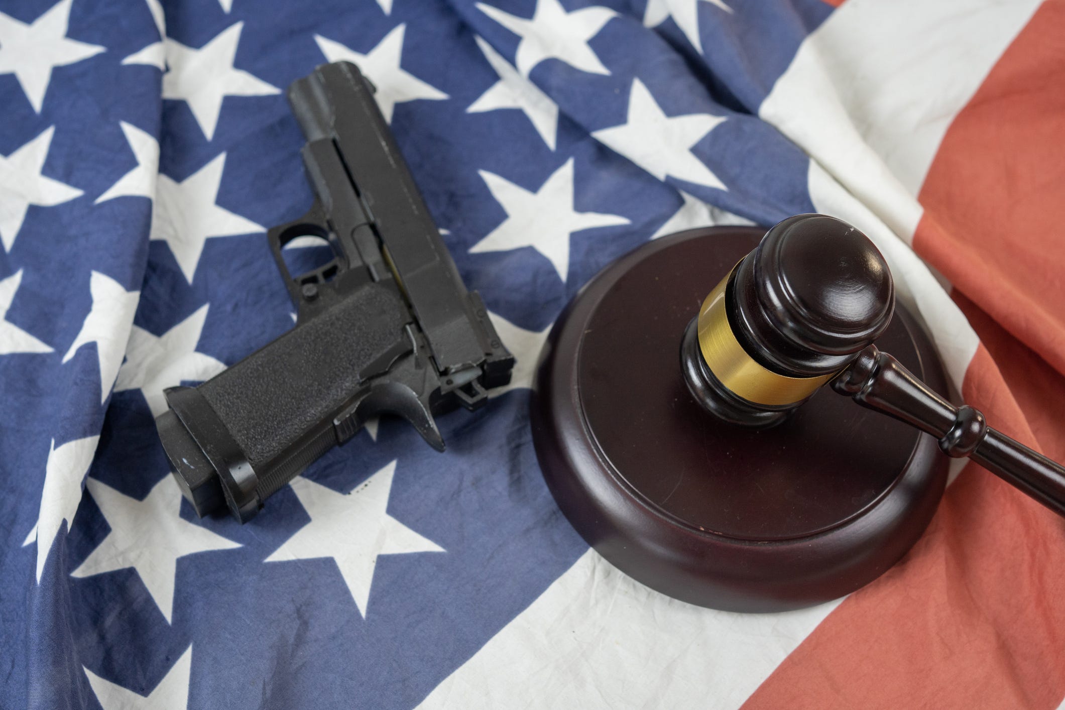 A gun and a gavel rest on the American flag.