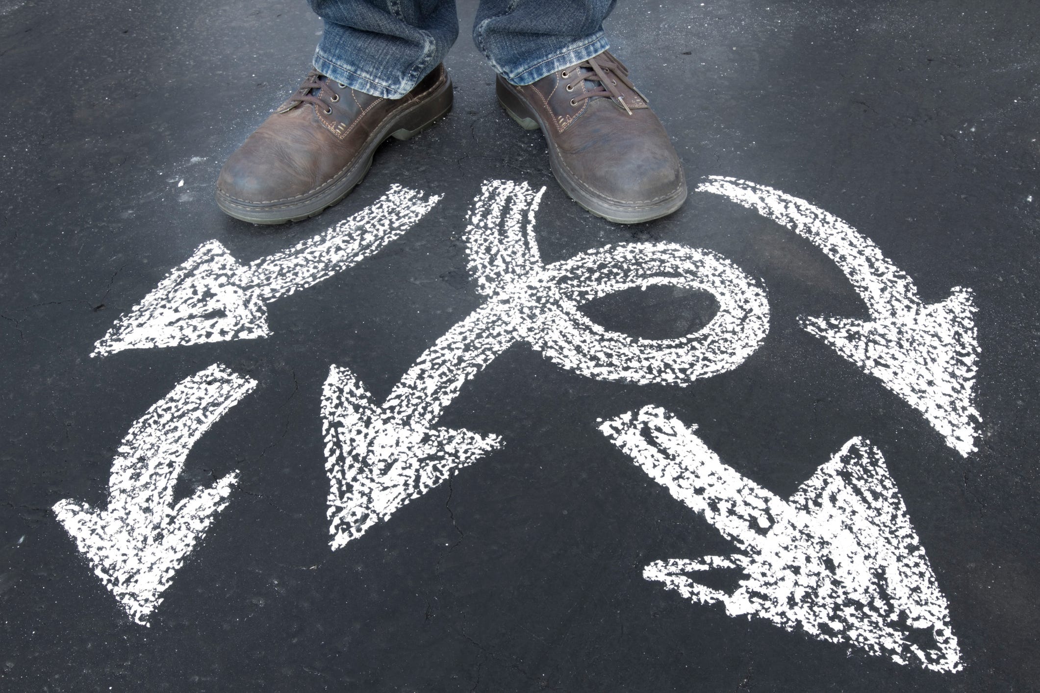 A man stands before arrows drawn in chalk.