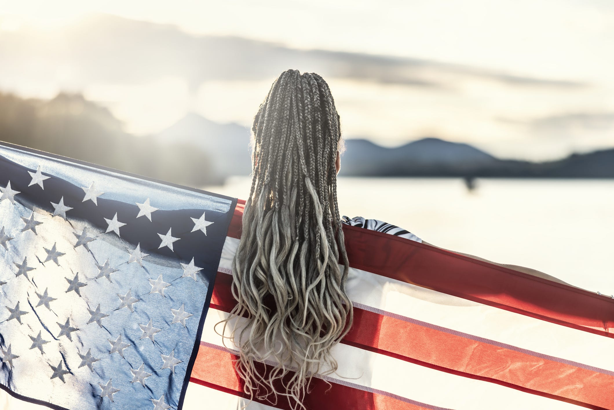 A woman holds the American flag over her shoulders.