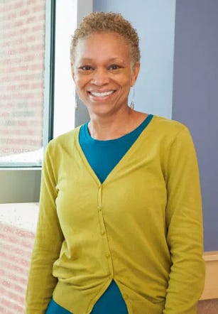 A black woman with short light hair wearing a cardigan