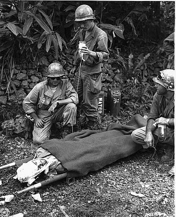 Capt. James R. Barron, Corpus Christi, Texas, is given plasma by front-line aid men after being wounded by a Japanese sniper on Okinawa. 4 April, 1945