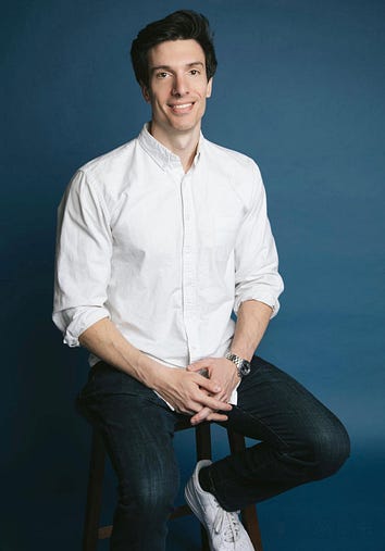 Photo of Rob Freund sitting on a stool against a blue background