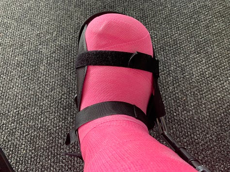 My healing foot in various stages of healing: A pink cast, a black surgical boot, and bandaged.