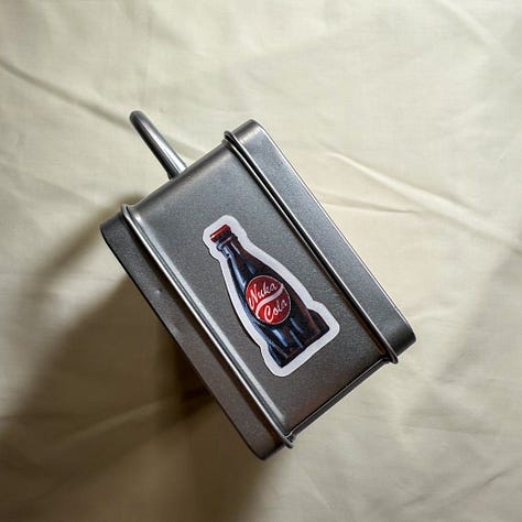 Silver lunchbox with nuka cola stickers