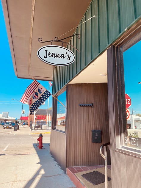 photo of a store front with a sign saying "Jenna's" out front; a gravel road between green trees and a blue sky; a small kitchen.