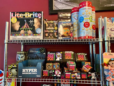 Left: girl standing in front of candy bins. Middle: open shelves with Care Bears, My Little Ponies, and other toys. Right: open shelves with Lite-Brites and other classic toys.