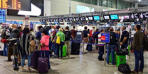 people with baggage waiting and lining up at airport
