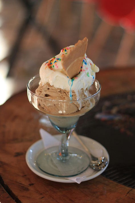 A gallery of photos, a loaf of rustic bread, a table with croissants, two seeded buns, a bowl of chocolate mousse, a scoop of vanilla and chocolate ice cream in a stemmed glass and a crunchy waffle topped with slices of fruit.