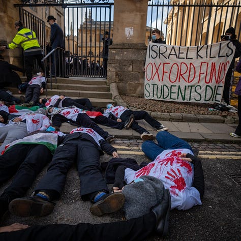 people wearing white t-shirts with red handprints on them lie on the steps outside the Sheldonian building in Oxford as others queue up in academic gowns. photos courtesy of @madeleine_observes