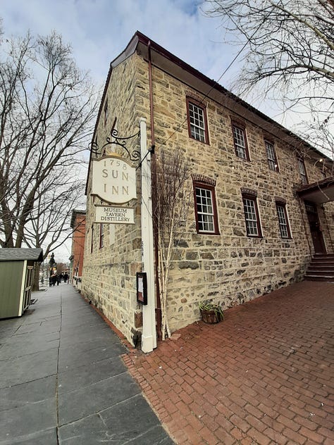 Pictures from Bethlehem, Pa., starting with the oldest waterworks in the United States, built in the 1700s. It's a stone building with cloudy sky. Next picture is three carriage horses standing in front of the 9-story tall brick Hotel Bethlehem, and a historic stone building that was used as a hospital during the Revolutionary War. Middle row is the Sun Inn Tavern, where almost all of our Founders ate and gathered at one time or another, The building is stone and there is white picket fence in the back and a porch with a red, white and blue banner on the side. Bottom row: Bethlehem's industrial park with original buildings made of stone against a blue sky. Last photo is the blacksmith busy at work in the blacksmith shop with a blazing fire.