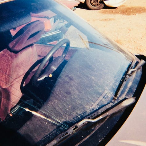 My champagne Mazda 626 lurches cockeyed in the wreck yard with other munched vehicles. The smashed front bumper lies on the ground. The windshield is lanced with cracks. The passenger side is caved in. The drivers side is demolished.