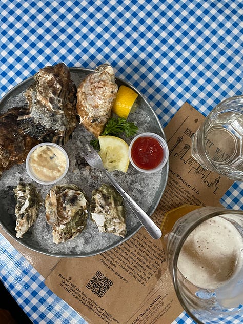 Inside Emmett's Oyster Bar in Seattle. Blue and white checkered table cloths, oysters, interior signage, and a sleeping dog. 