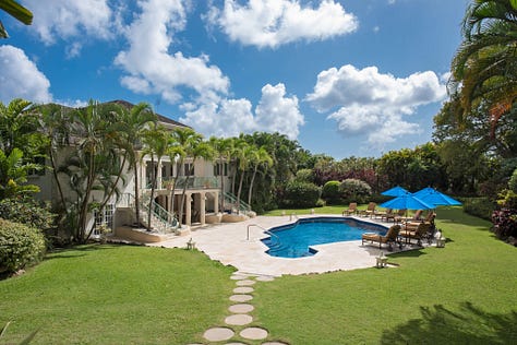 Elegant Villa Aliseo in Barbados’ Sandy Lane Estate, surrounded by lush tropical gardens, featuring an expansive swimming pool, private tennis court, and sophisticated outdoor dining area on the large terrace. The luxurious nine-bedroom villa offers a perfect blend of privacy and indulgence.