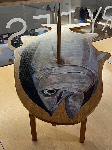 Two images of a wooden table carved into the shaped of a tuna fish with a painted tuna fish painted on top