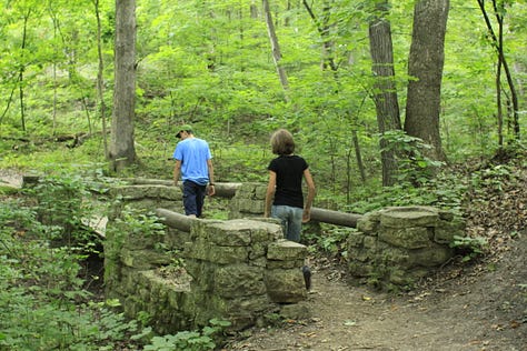 Photos of a heavily wooded trail with two people hiking and posing along the trail