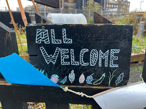 The Mobile Garden in Hackney Bridge, with planters and various crops, a polytunnel and signage saying "ALL WELCOME"