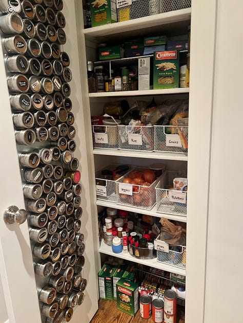 Large pantry with magnet spice wrack on the open door and storage containers on the shelves.