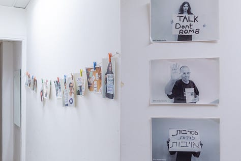 Itach Ma'akiではパレスチナ人とイスラエル人が共に活動している｜事務所で作業するスタッフ達｜廊下に掲げられた平和に向けたメッセージを掲げる市民の写真