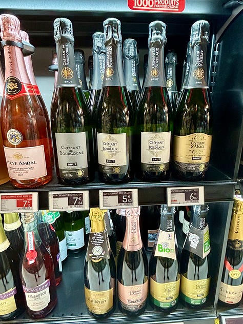 Bottles of different sparkling wines rest on shelves in a French market