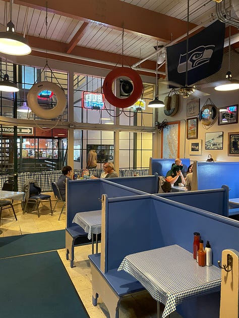 Inside Emmett's Oyster Bar in Seattle. Blue and white checkered table cloths, oysters, interior signage, and a sleeping dog. 