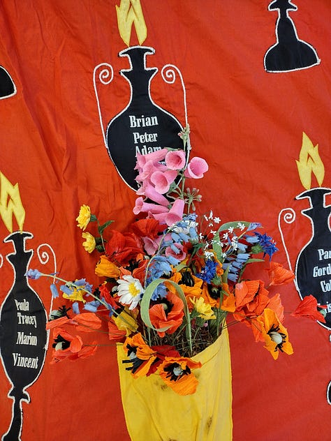 Brightly coloured paper poppies and paper wildflowers arranged in the red and yellow Hillsborough Memorial Banner
