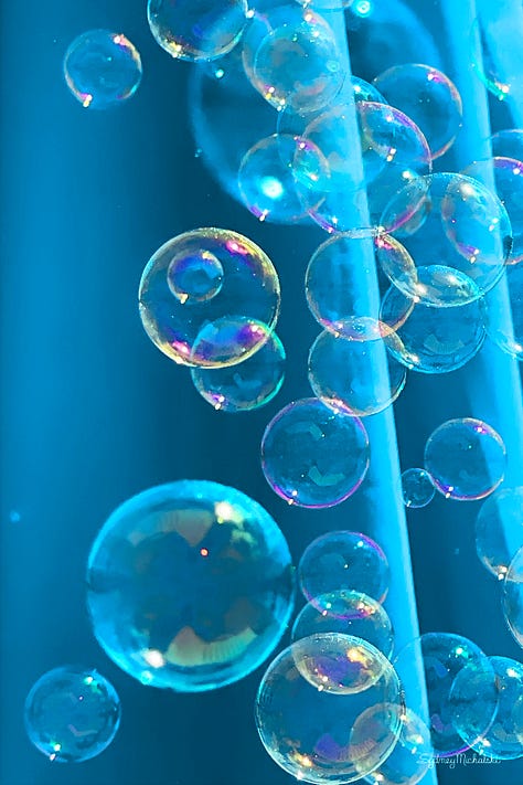 A series of three images features colorful bubbles drifting past a turquoise beach umbrella.