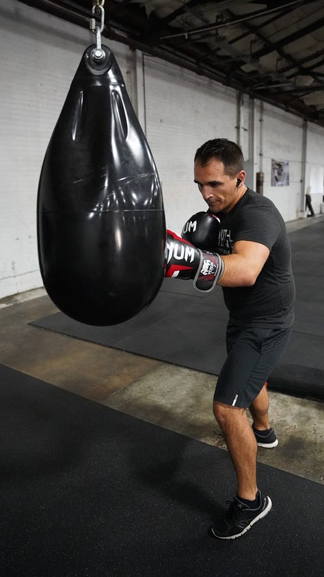 Brian hitting a punching bag at the back of a gym.