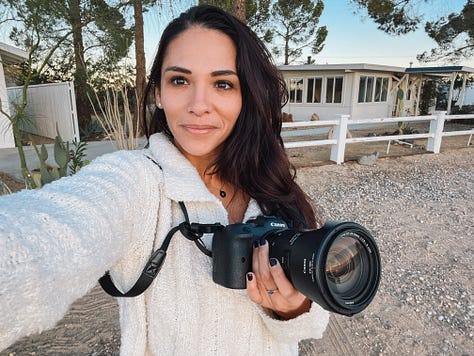 One row of three photos, left to right: Selfie photo of woman holding up her digital camera with sandy, gravelly driveway in the foreground and white one-story buildings in the background; Photo of woman standing in a darkened crevice, on boulders wedged between larger boulders and slabs of rock; Selfie photo of two women smiling atop a hill on a hike overlooking low lying hills that fall away to the Pacific Ocean.