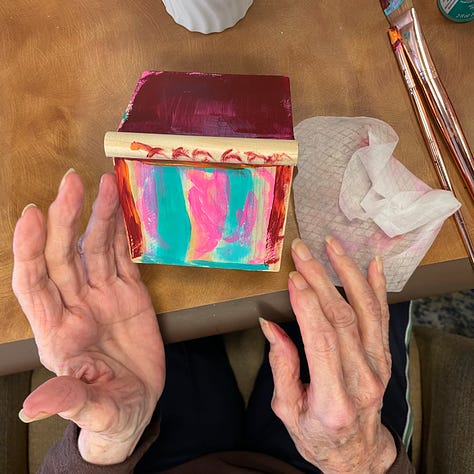 Hands, young and old, arrange bouquets and paint wooden birdhouses together. 