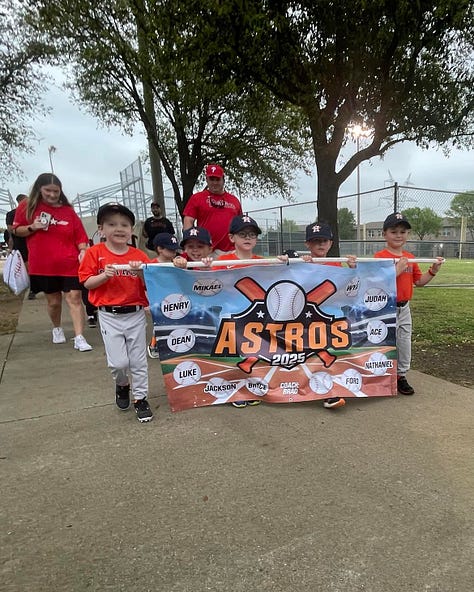 Little boys in baseball uniforms carrying banners bearing their names