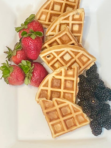 A platter with waffles and strawberries and then blue berries and then complete with bagels, cream and butter