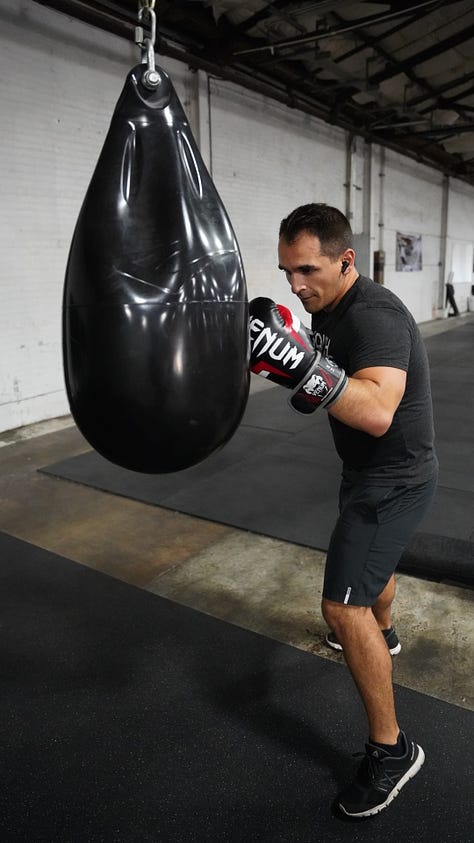 Brian hitting a punching bag at the back of a gym.