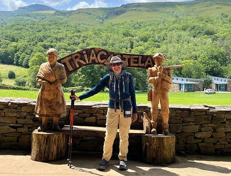 Beautiful mountain scenery. Marcella standing in front of a carved wooden sign flanked by two carved figures.