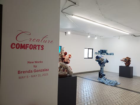 A grid of 9 photos. Four images are photos of the opening of Brenda Gonzalez's show, "Creature Comforts," at Arts at Blue Roof. Five images are photos of the installed sculptures and prints in the show. 