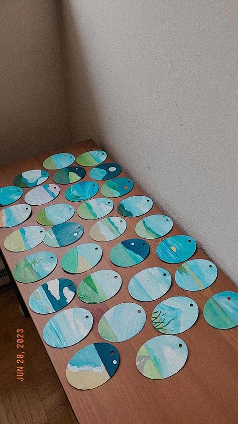 A gallery of small acrylic paintings on an oval shaped cardboard.