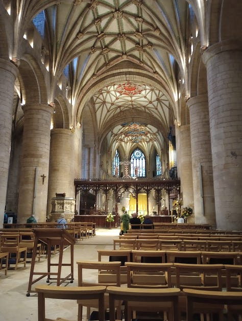 Exterior side of stone building with clock tower, interior with large stained glass window, interior with smaller stanined glass windows, altar, and ceiling decoration that looks like large star, large star, gift shop fll of merch in side chapel, cake slice and cup of tea